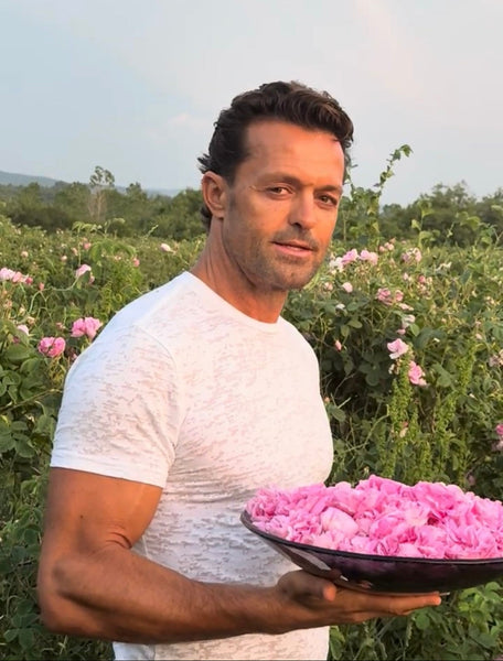 Man holding a bowl of pink flowers in a field