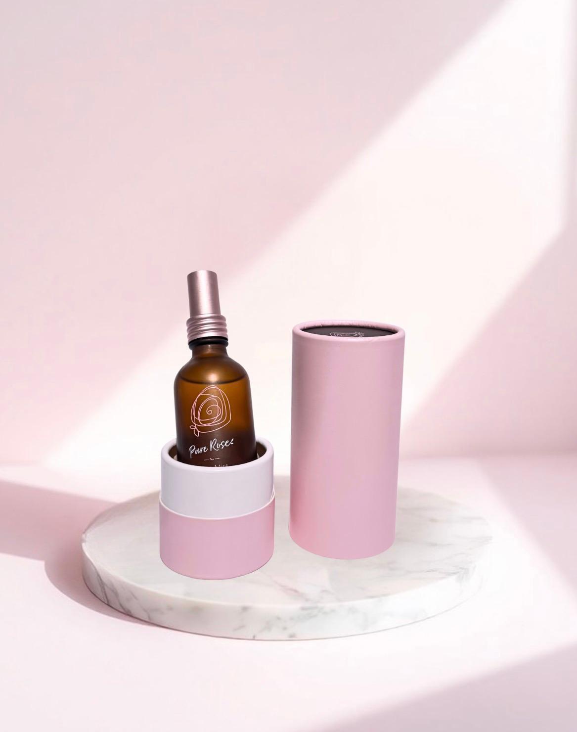 Rose Mist bottle in its open pink tube on a marble stand