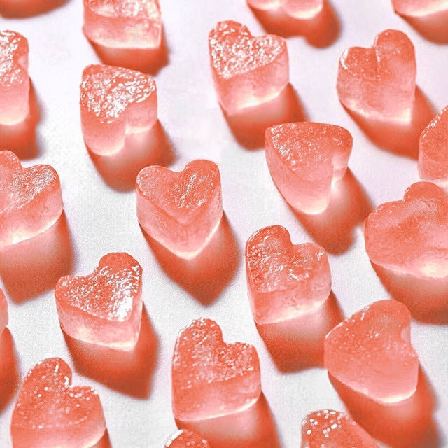 Coral heart-shaped Rose Yummies gummies spread on a white surface