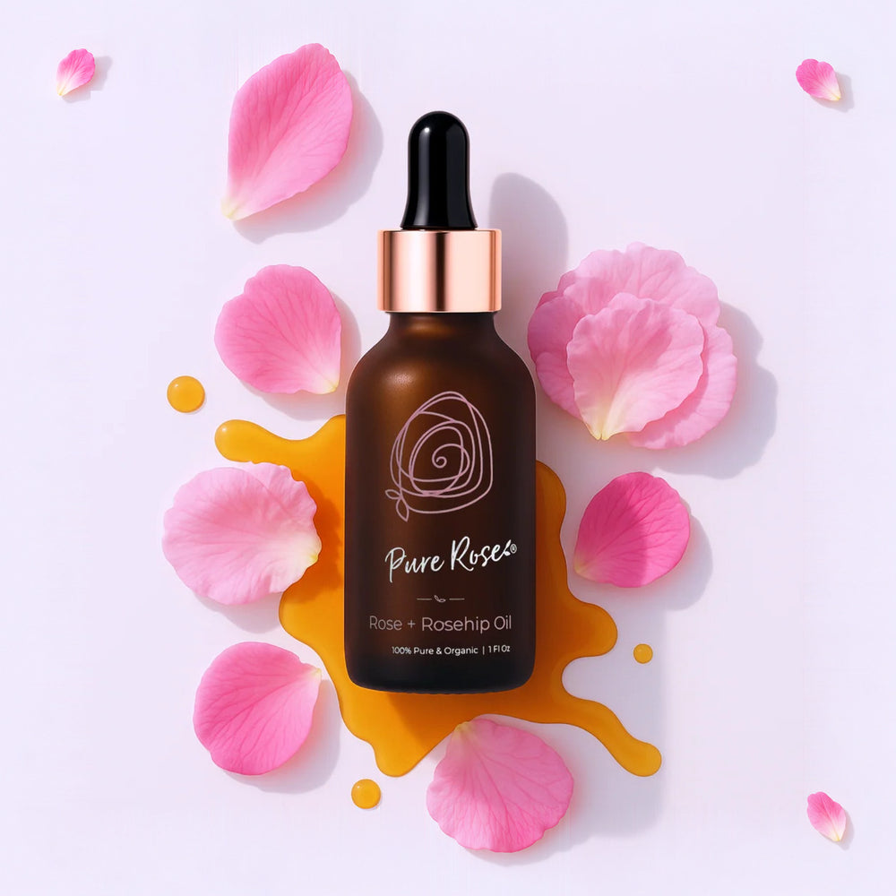 Rose + Rosehip Oil dropper bottle among pink rose petals and a golden oil splash